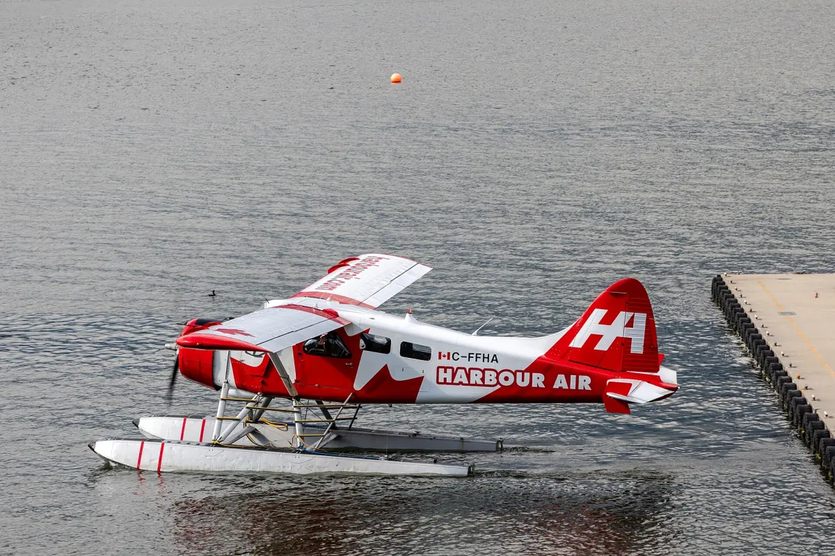 Red and white Harbour Air seaplane floating beside a dock in Vancouver