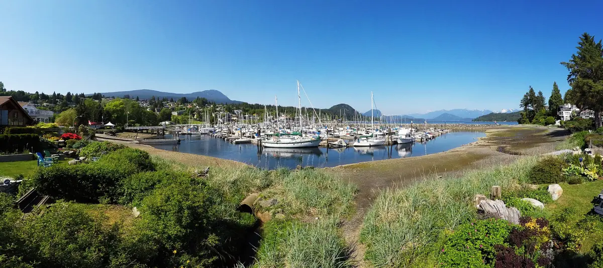 Marina and green waterfront park in Gibsons with mountains behind