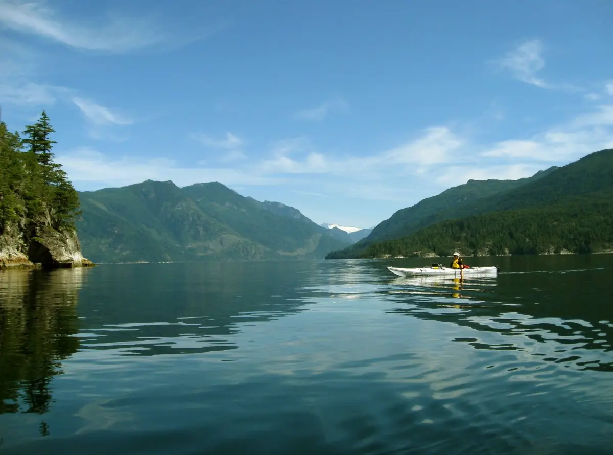 Green still water of Sechelt Inlet between steep forested mountains